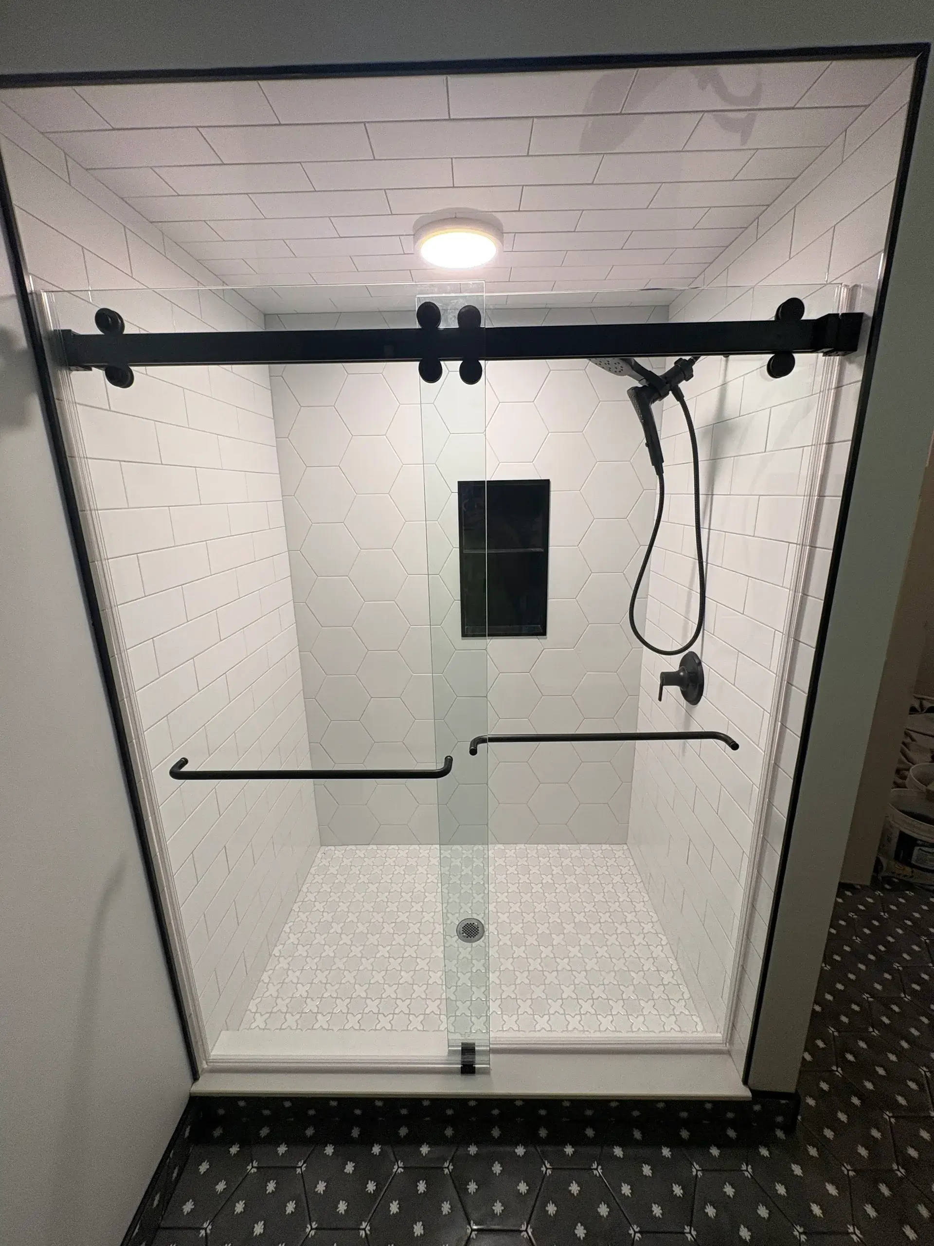 Modern shower with glass doors and hexagonal tiles.